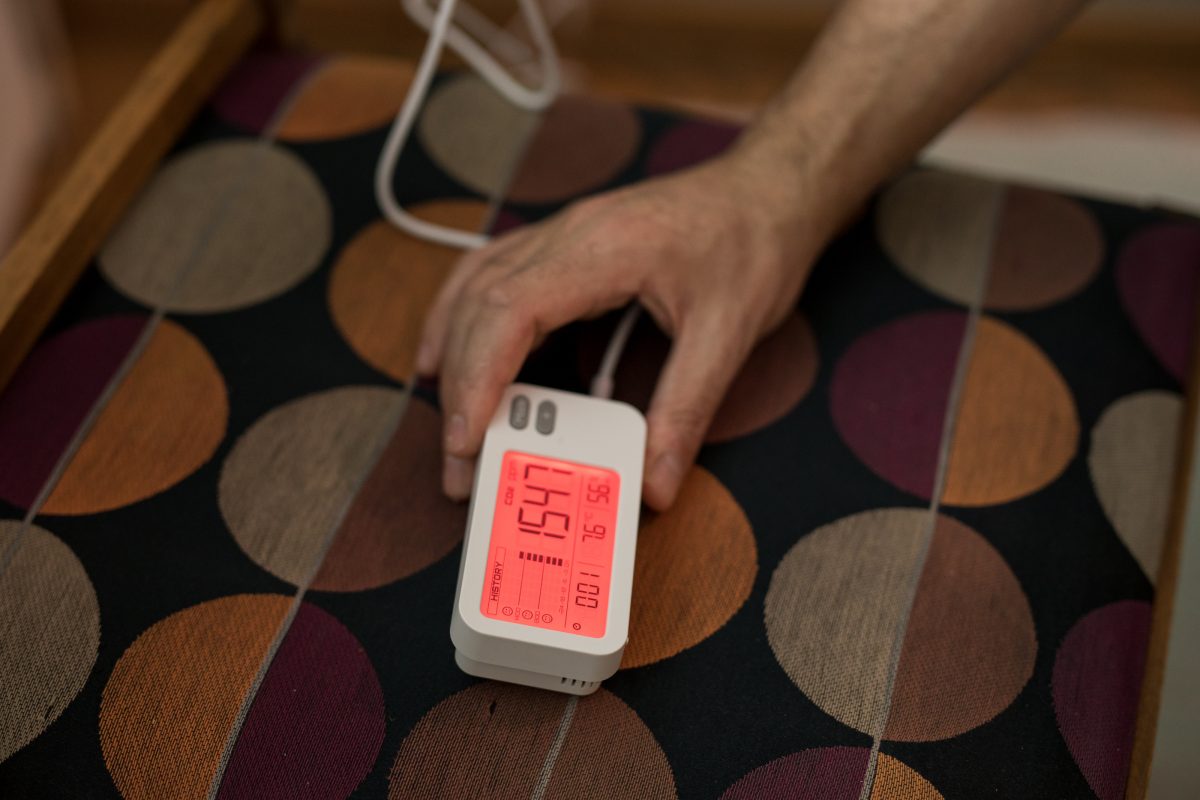 Henkilö mittaa huoneen ilmanlaatua olosuhdemittarilla.